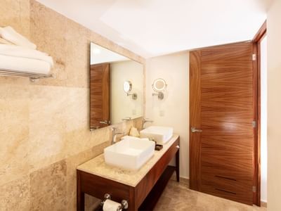 Bathroom interior with dual sinks, large mirror, and wooden door at Buenaventura Grand Hotel and Spa