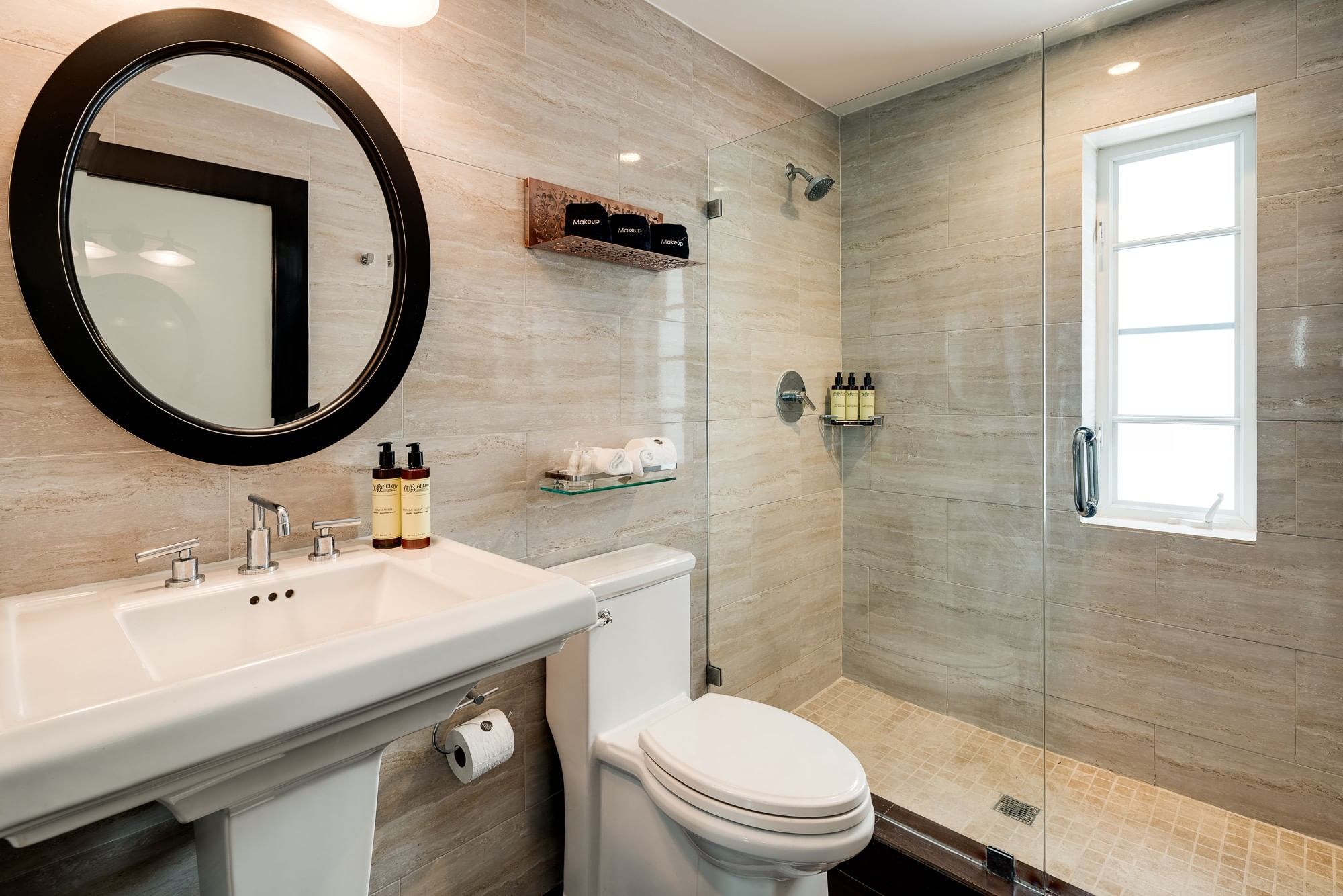 A clean bathroom with a toilet, shower, sink, and mirror.