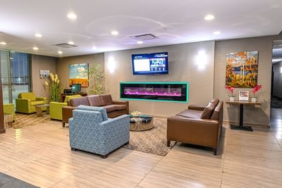 Interior view of the lobby area with cozy sofa and a TV at Encore Suites Grande Prairie