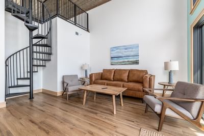 Stylish living room with a spiral staircase, leather sofa, and wooden coffee table in the villa at Off Shore Resort