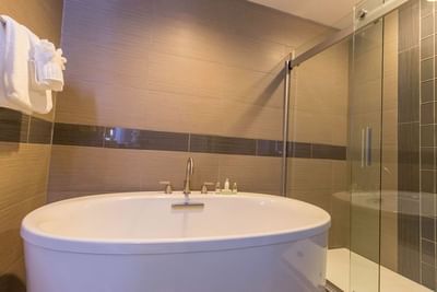 A clean, modern bathroom with a large white standalone soaking tub and a walk-in glass shower at The Stanley Hotel