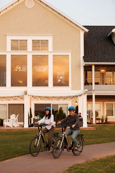 Smiling man and woman riding electric bicycles on a paved path at the Rodd Crowbush Golf & Beach Resort