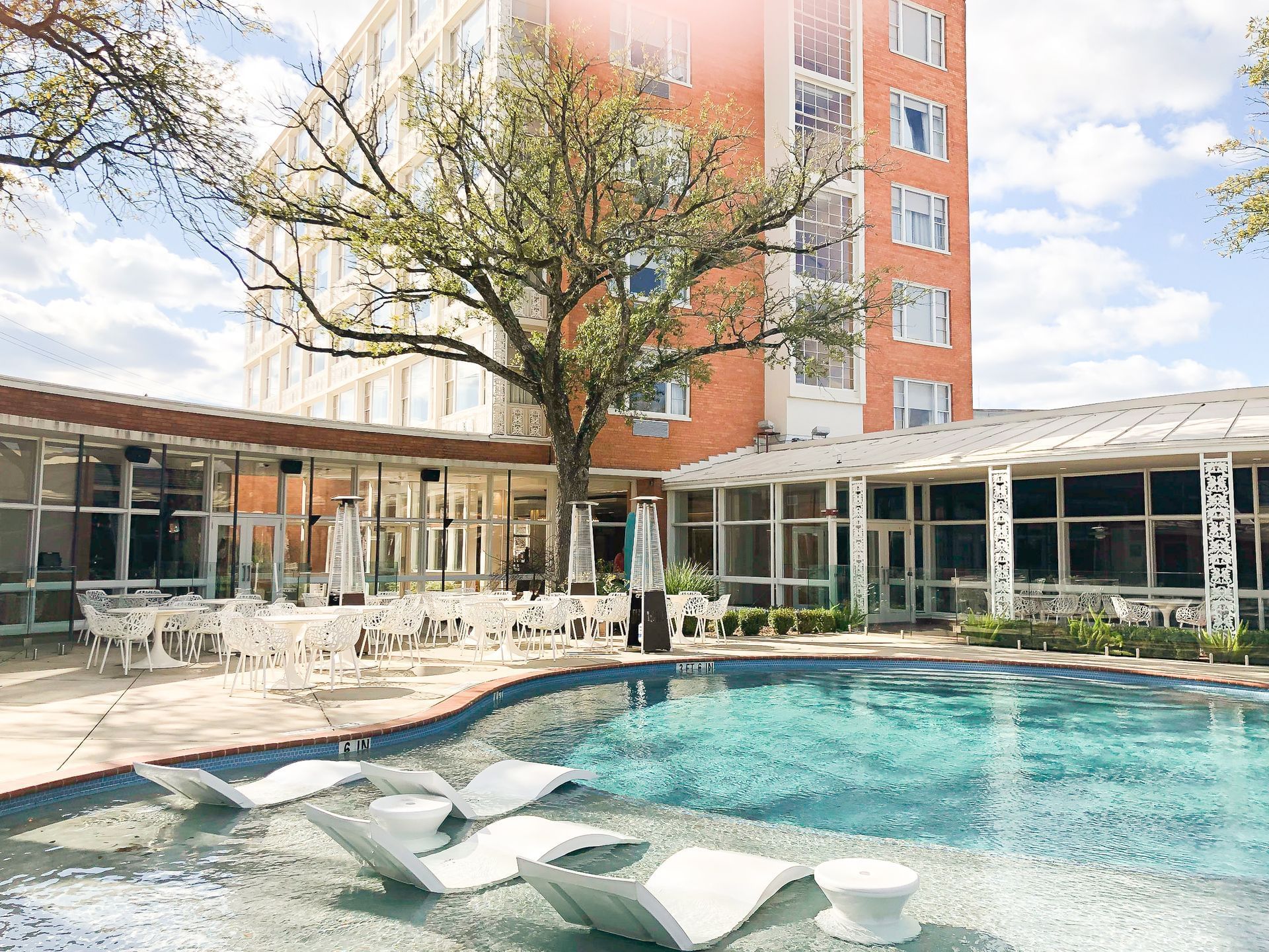 Cabana pool and sun beds with the exterior of The Fredonia Hotel