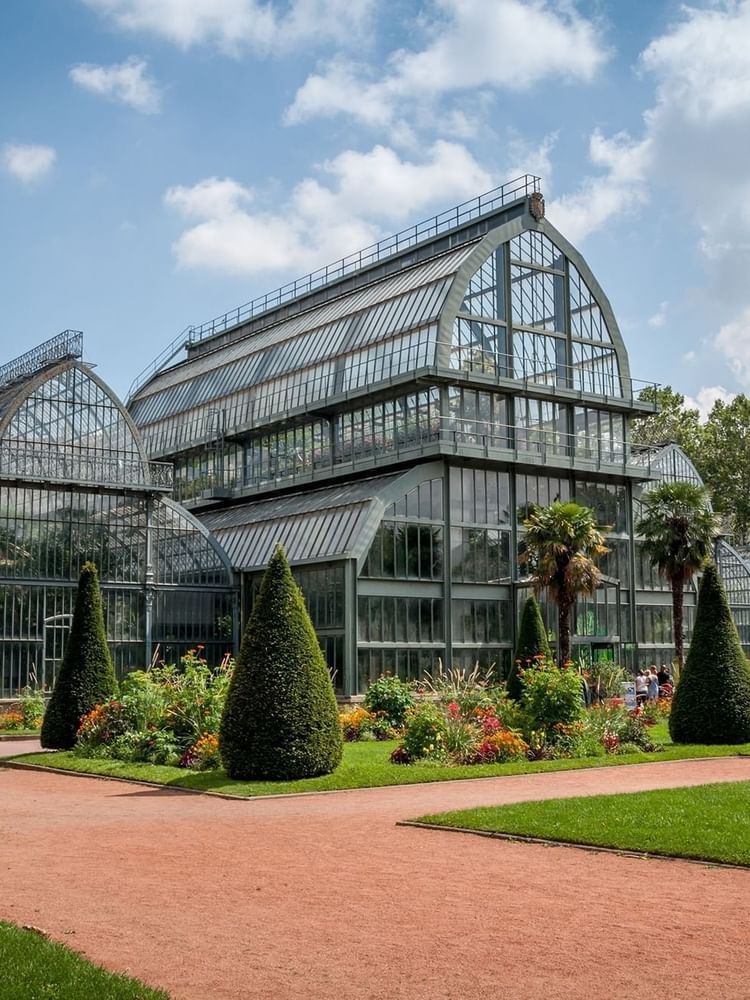 The exterior of Tete d’Or Park with a multi-sectioned glass greenhouse near Warwick Reine Astrid - Lyon