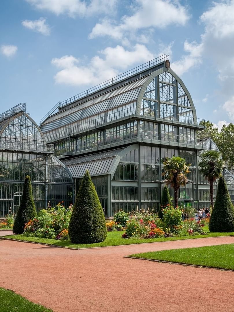 The exterior of Tete d’Or Park with a multi-sectioned glass greenhouse near Warwick Reine Astrid - Lyon