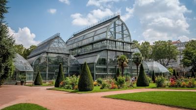 The exterior of Tete d’Or Park with a multi-sectioned glass greenhouse near Warwick Reine Astrid - Lyon