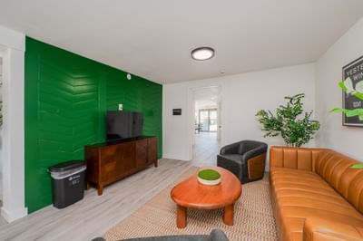Tan leather sofa and grey armchairs facing a scoreboard wall art at The Varsity South