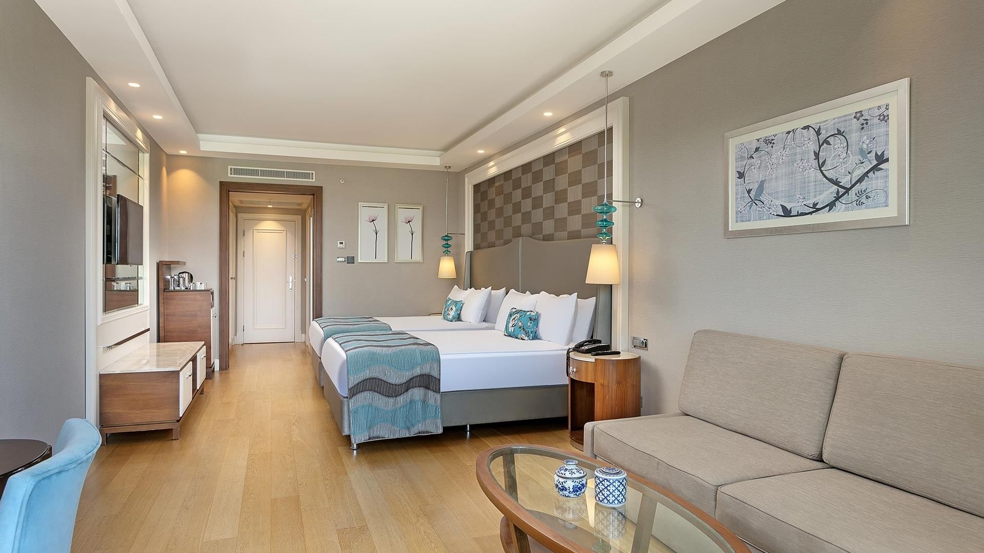 Titanic Deluxe Golf Belek’te Superior Oda’da yatağın yanında oturma alanı ve TV.