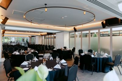 Spacious event venue with banquet set-up, frosted glass windows, and modern lighting at Amora Herencia Riverwalk Melbourne