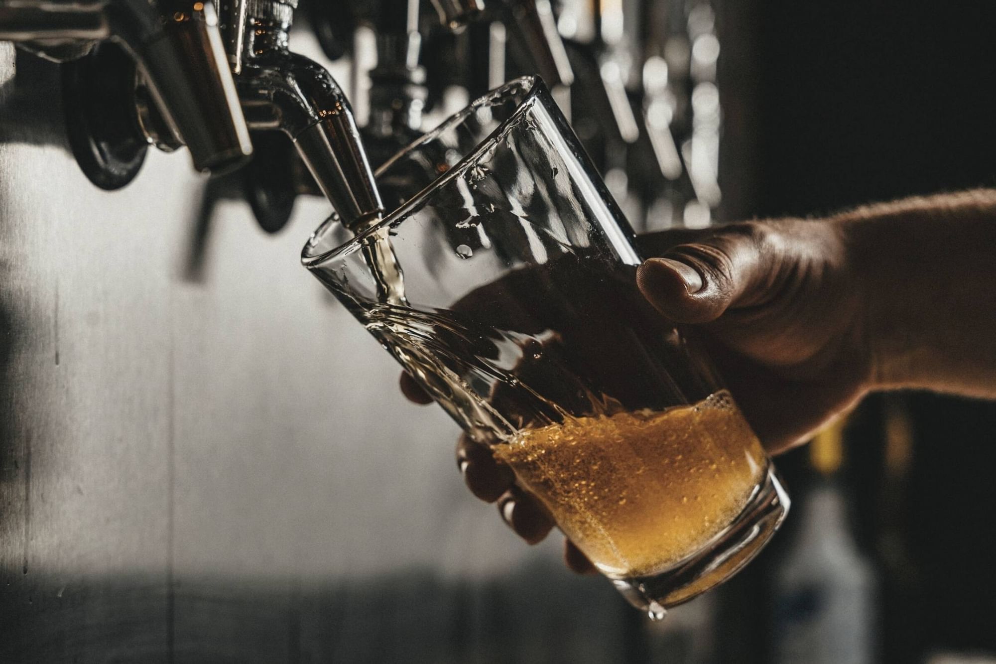 A person pouring beer to a glass in Waikiki Brewery near Waikiki Resort Hotel