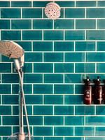 Showerhead and toiletries in a blue-tiled shower area at Warwick Deluxe Rooms in Korolevu at Warwick Fiji Resort and Spa.