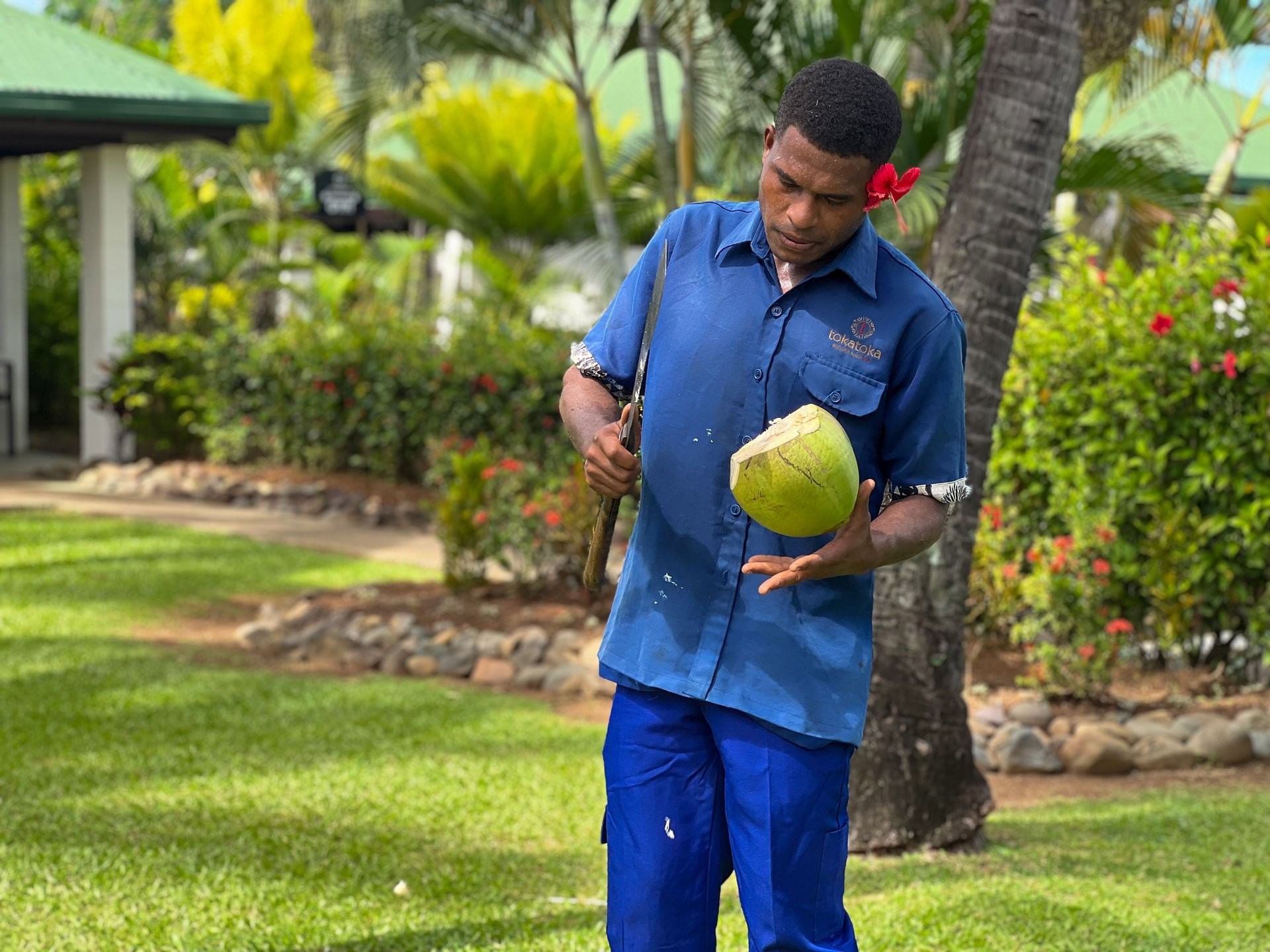Man in blue holding a coconut and a knife at TokaToka Resort Nadi Fiji نادي
