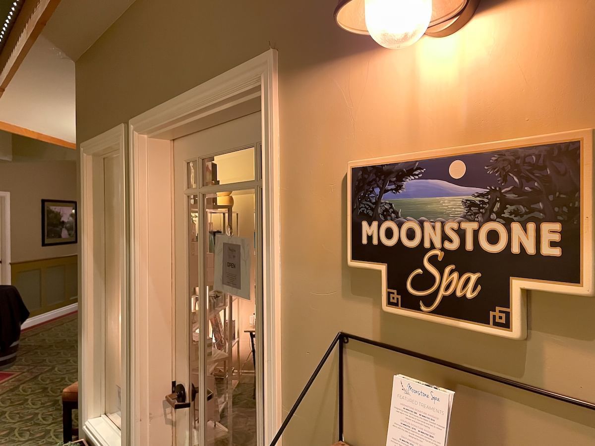 Moonstone Spa sign with scenic artwork, illuminated wall light, and open glass door in a hallway.