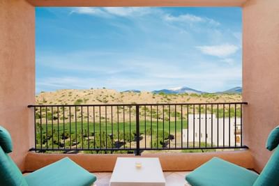 Balcony at Hilton Santa Fe Buffalo Thunder with two comfy chairs, overlooking the golf course and distant mountain views