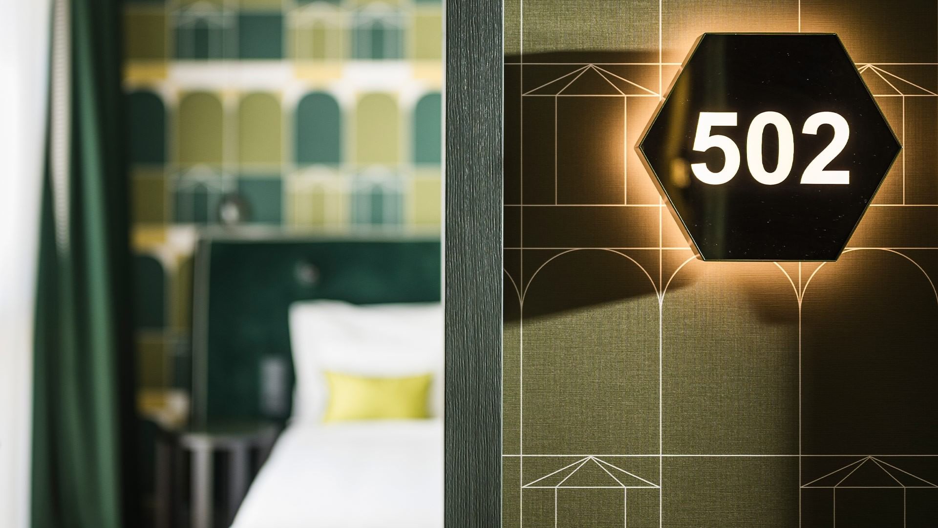 Illuminated room number 502 on a wall beside a Superior Room bed at Falkensteiner Hotel Bozen WaltherPark, Bolzano.