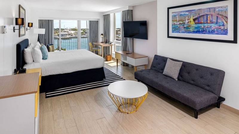 King-size bed, work desk, a TV & a cozy couch in Harbor Premium Balcony at Warwick Paradise Island Bahamas