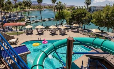 Pool with turquoise water slides, patio umbrellas, and marina views with palm trees at London Bridge Resort