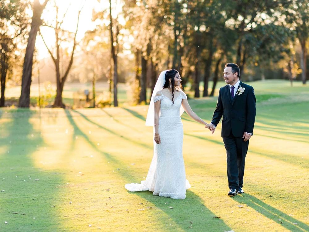 couple walking on a golf course during a wedding at Mercure Kooindah Waters