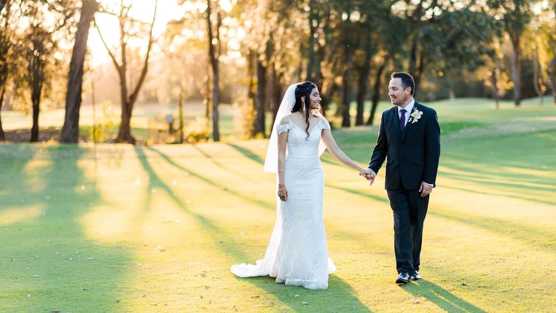 couple walking on a golf course during a wedding at Mercure Kooindah Waters
