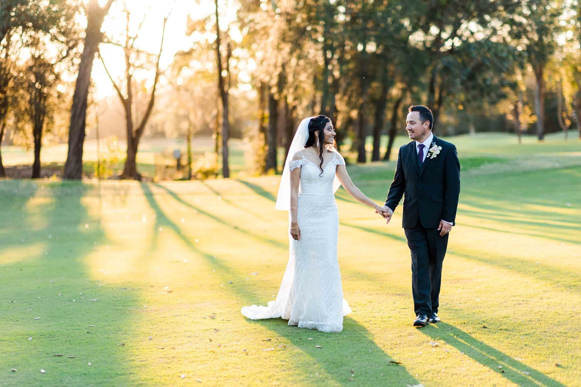 Bride and groom walking in outdoors holding hands at Mercure Kooindah Waters