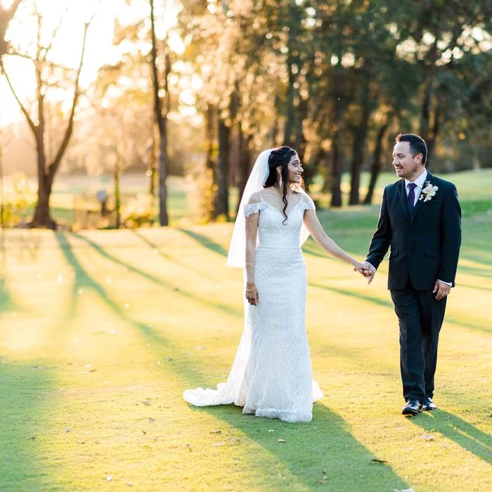 A bride and groom walking hand in hand near Mercure Kooindah Waters