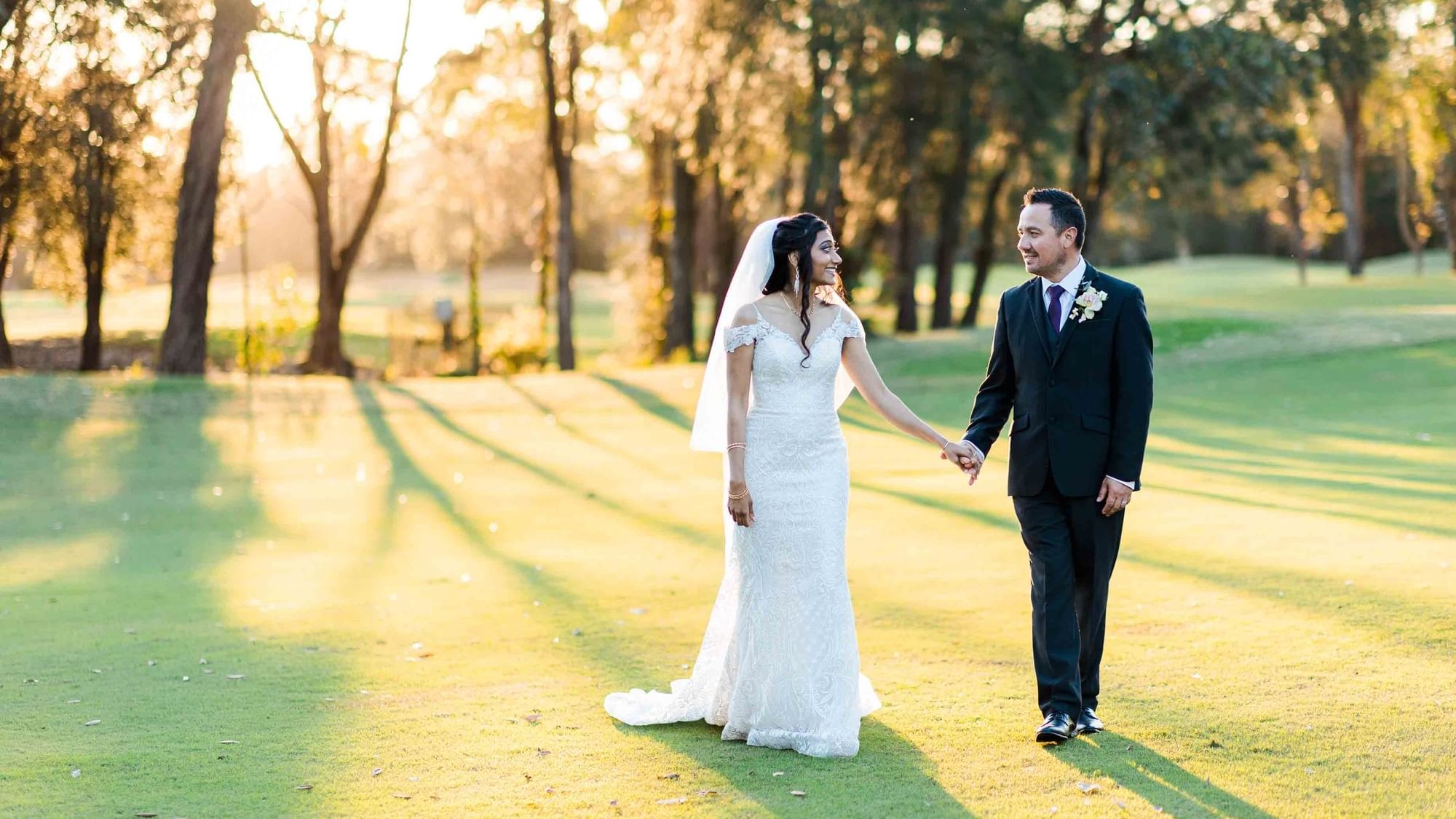 A bride and groom walking hand in hand near Mercure Kooindah Waters