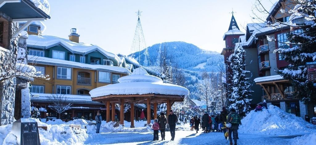 Winter scene in Whistler Village with snow covered buildings shops and pedestrians