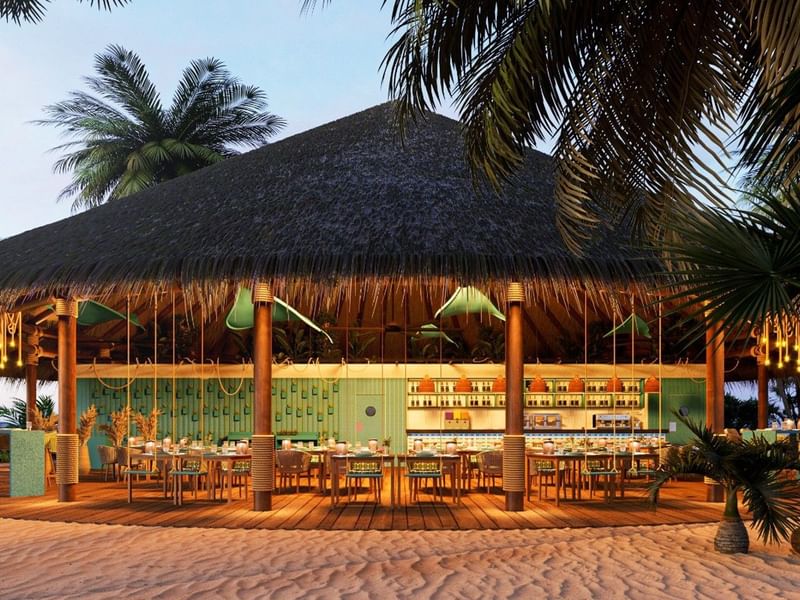 Restaurante con techo grande de palma en Fiesta Americana Funeeq Punta Cana con área de comedor exterior y arena de playa