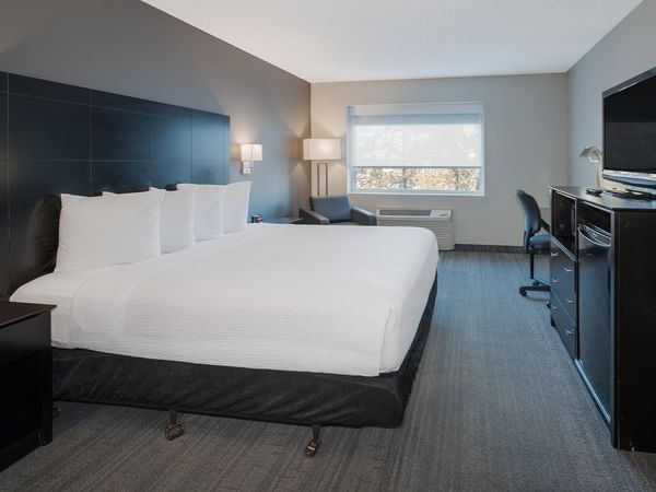 Hotel room with a king bed, modern furniture, and a TV.