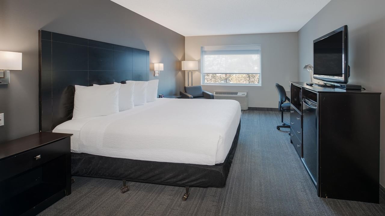 Hotel room with a king bed, modern furniture, and a TV.