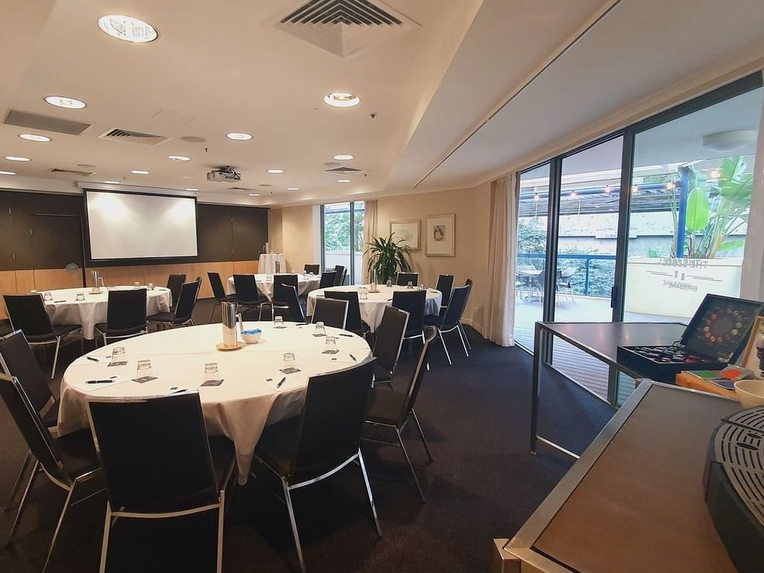 Albert I Room with round tables, a presentation screen, and a coffee station near the glass doors at The Sebel Brisbane