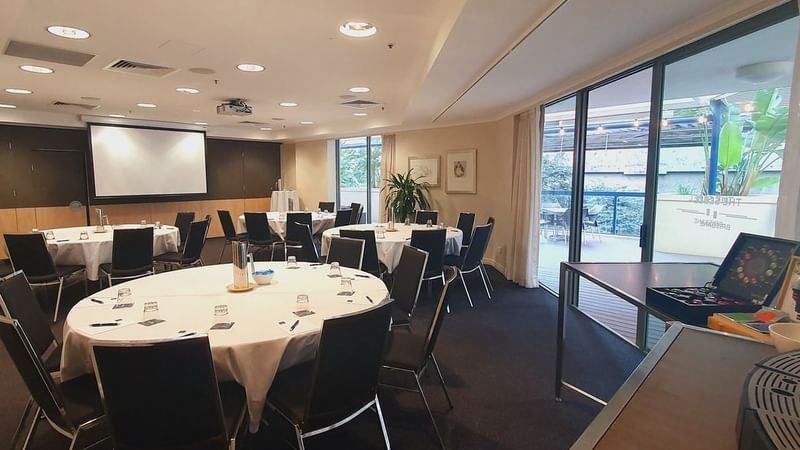 Albert I Room with round tables, a presentation screen, and a coffee station near the glass doors at The Sebel Brisbane