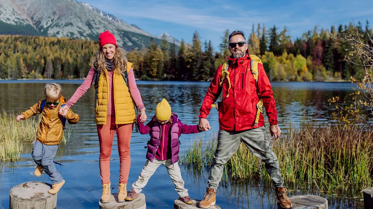 family of four standing on stumps on a lake
