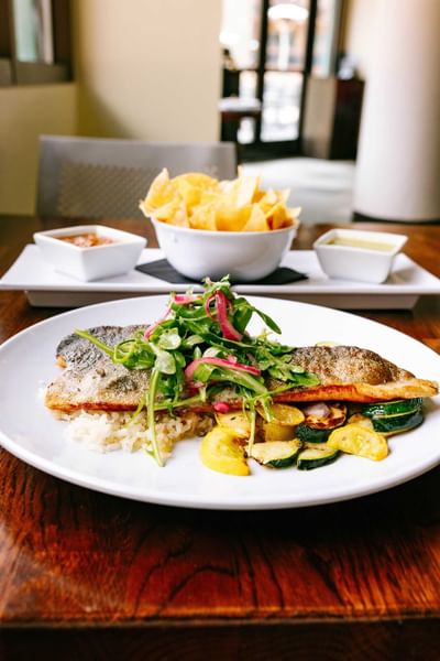 Plate with fish, vegetables, and rice with a bowl of chips at Elevation Resort Spa