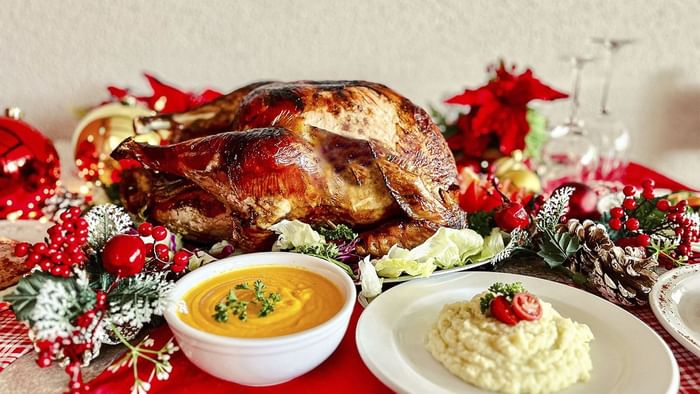 Pavo asado con adornos festivos, sopa y puré de papa en mesa navideña de La Pérgola de Araiza Palmira 