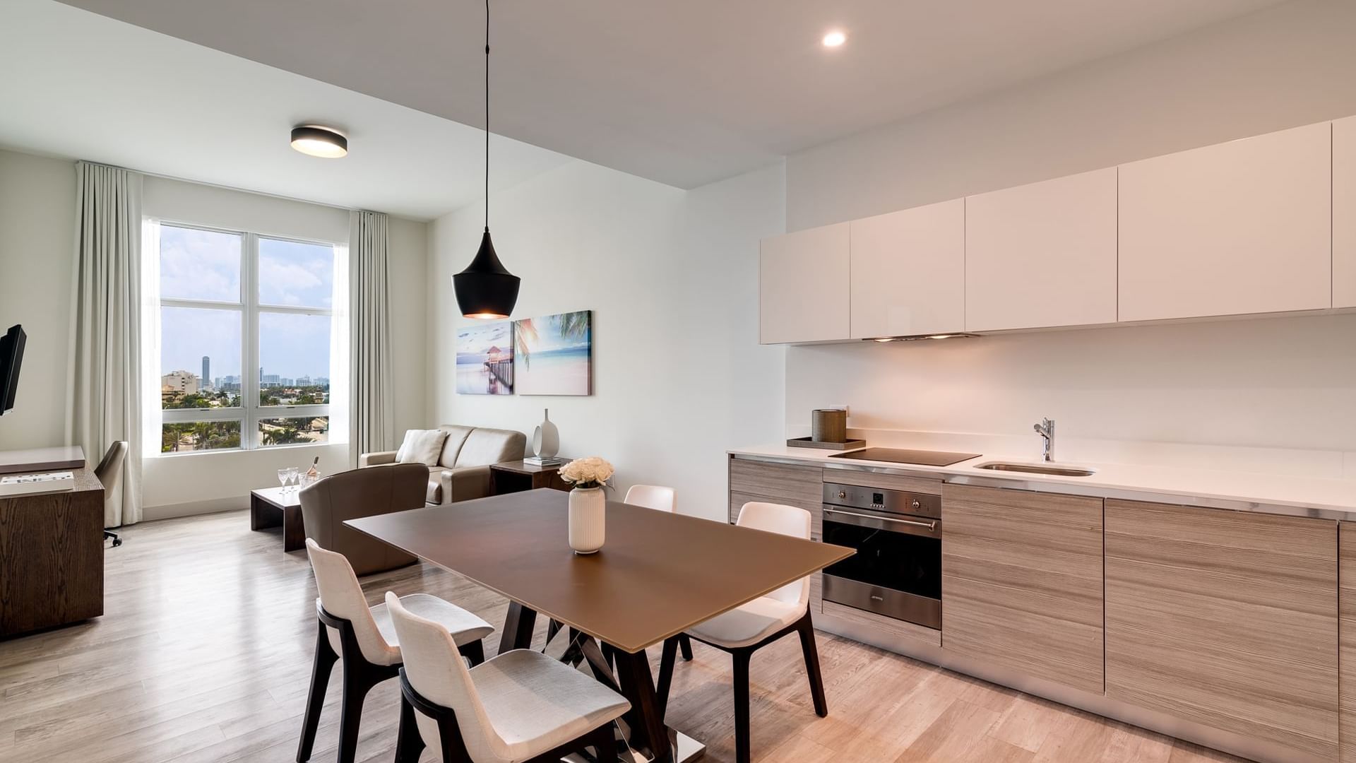 A modern open-plan living space with kitchen, dining area, and living room, featuring a city view.