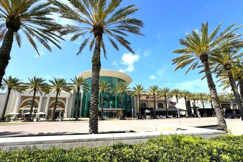 The exterior of the main entrance of Mall at Millenia, surrounded by palm trees. 