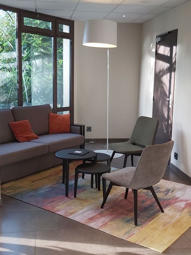 Chaises, canapé et tabourets dans le lobby à Oceania Nantes Aéroport