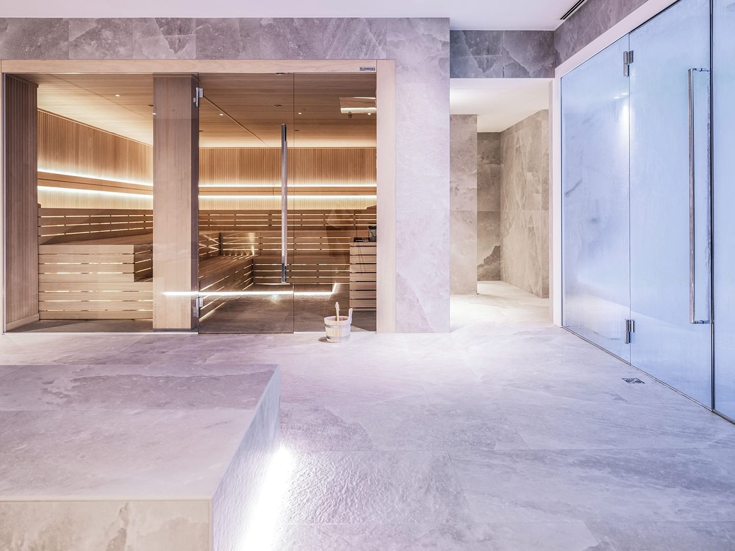 Interior of a modern spa with glass doors, wooden benches, and a clean, minimalist design.