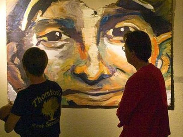 People viewing art on a wall near MCM Eleganté Suites