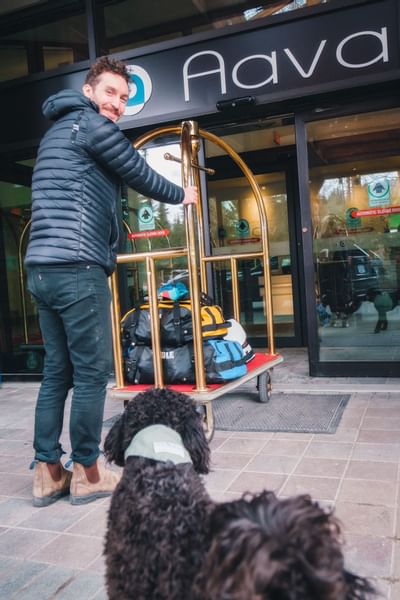 Guest pulling a luggage cart by entrance, Aava Whistler Hotel