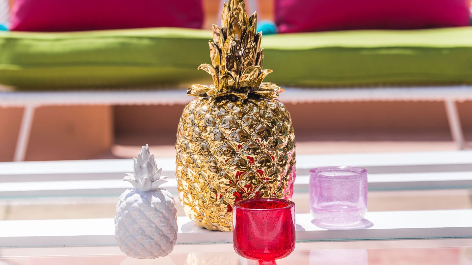 Delfines Bar table with two pineapple sculptures and pink and red glass candle holders at Hacienda del Mar Los Cabos.