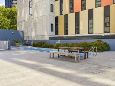 A pool with benches and a building at Student Living Auckland Anzac.