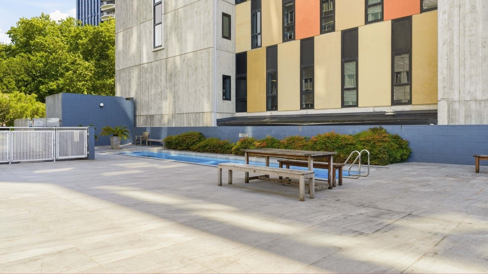 A pool with benches and a building at Student Living Auckland Anzac.