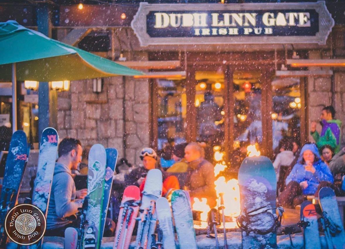 Illuminated Dubh Linn Gate Irish Pub exterior with people outdoors at Blackcomb Springs Suites