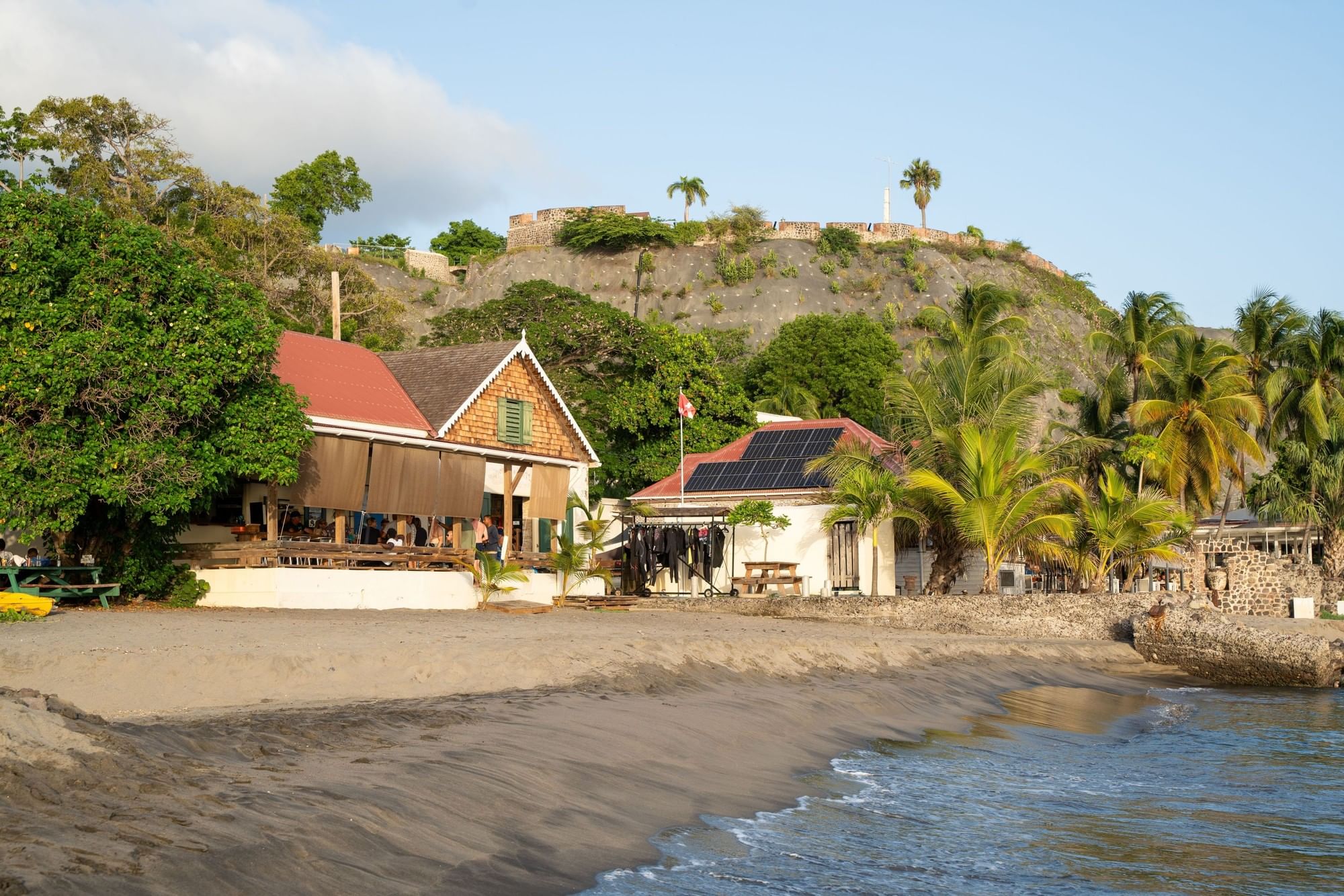 Beachfront Sint Eustatius with solar panels on the roof, under a coastal hillside under a blue sky at Golden Rock Resort