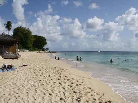 Sandy beach with people swimming and lounging at The Beach House near All Seasons Resort Europa