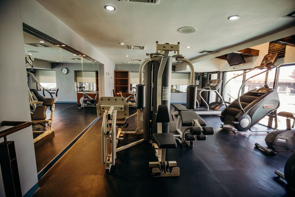 Gimnasio equipado con máquina de pesas, cinta de correr, bicicleta estática y espejo grande en Araiza Calafia