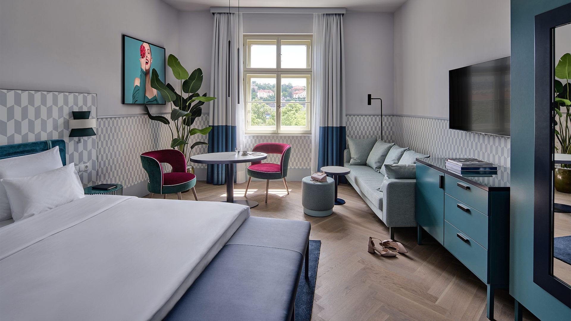 Bed, sofa & TV in Superior Room at Falkensteiner Hotels