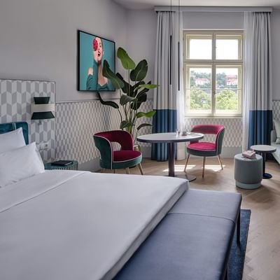 Bed, sofa & TV in Superior Room at Falkensteiner Hotels